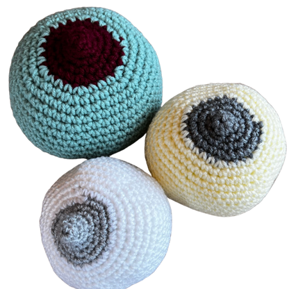 crocheted breast models to teach prenatal clients how to latch a baby at the breast. One large breast, mint green with a burgundy large nipple, one medium small cream coloured with a grey flattish nipple and one small white coloured breast with a grey perky nipple.