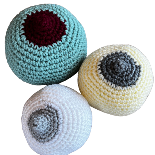 crocheted breast models to teach prenatal clients how to latch a baby at the breast. One large breast, mint green with a burgundy large nipple, one medium small cream coloured with a grey flattish nipple and one small white coloured breast with a grey perky nipple.